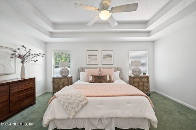 carpeted bedroom with ceiling fan and a raised ceiling