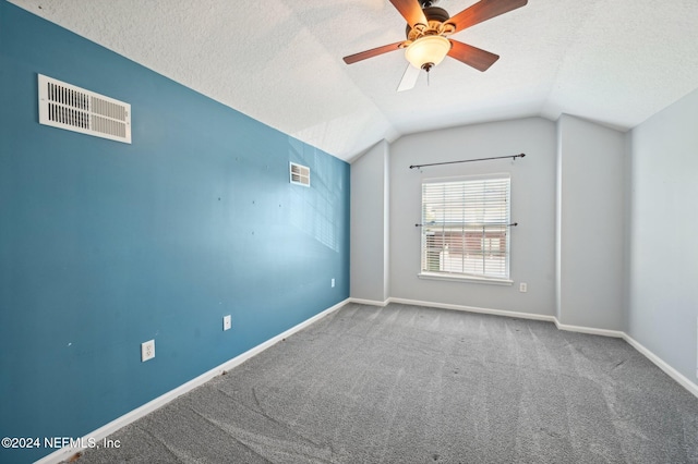 carpeted empty room featuring ceiling fan, a textured ceiling, and vaulted ceiling