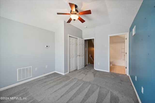 unfurnished bedroom with carpet, ceiling fan, a closet, vaulted ceiling, and connected bathroom