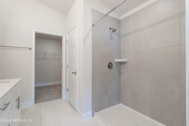 bathroom featuring vaulted ceiling, vanity, and a tile shower