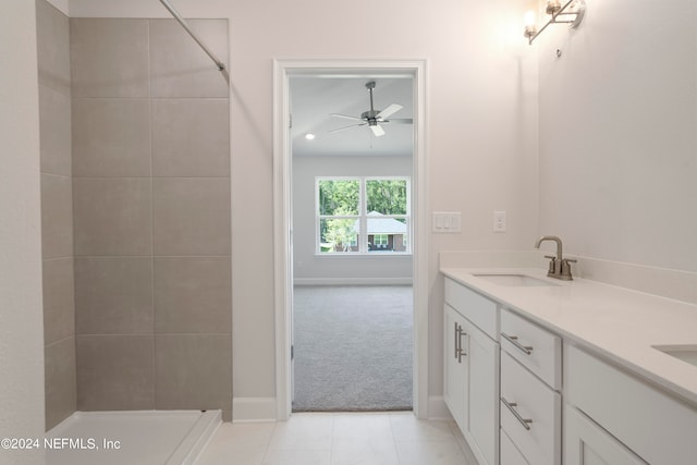 bathroom with ceiling fan, tile patterned flooring, tiled shower, and vanity