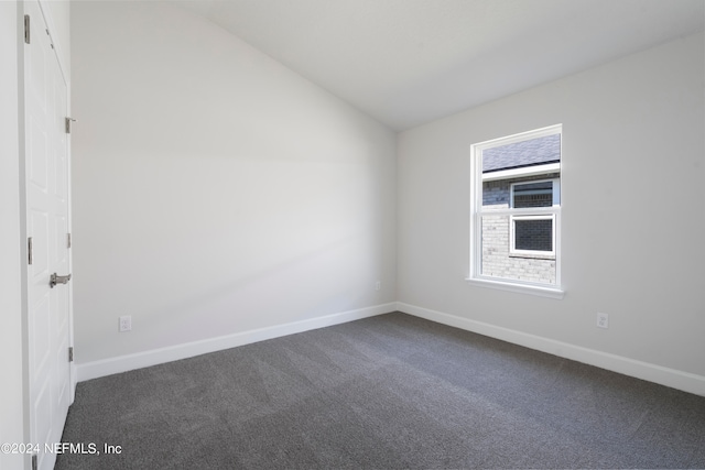 carpeted spare room featuring vaulted ceiling