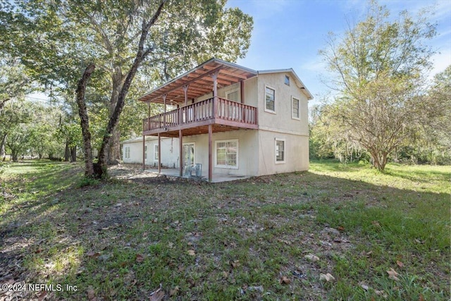 back of property featuring a wooden deck, a yard, and a patio