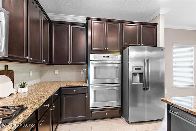 kitchen featuring appliances with stainless steel finishes, light tile patterned flooring, ornamental molding, and light stone counters