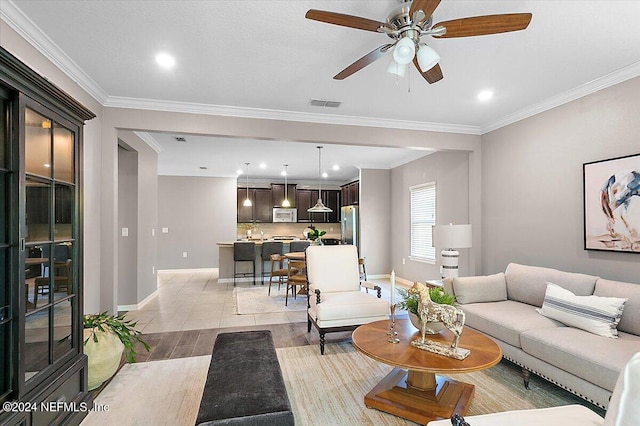 living room with crown molding, light wood-type flooring, and ceiling fan