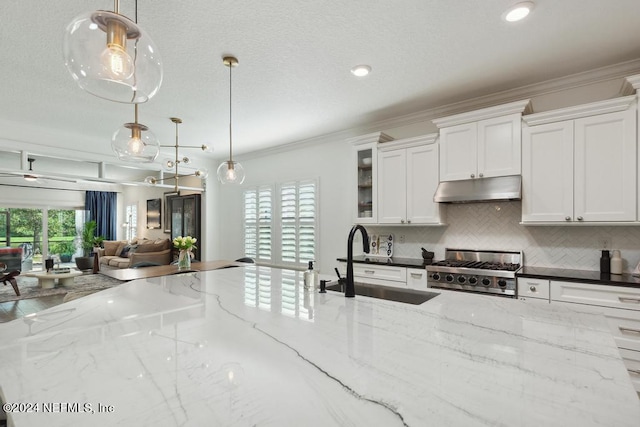 kitchen featuring stainless steel range, hanging light fixtures, dark stone countertops, sink, and white cabinets