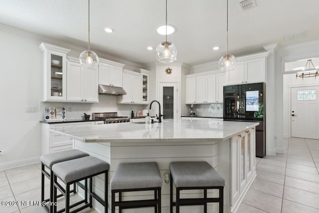 kitchen featuring fridge, light tile patterned floors, under cabinet range hood, backsplash, and visible vents