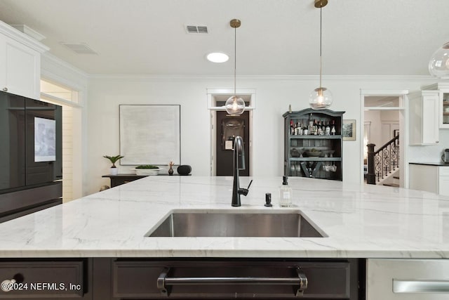 kitchen with white cabinets, light stone countertops, decorative light fixtures, and sink