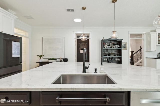 kitchen featuring visible vents, pendant lighting, crown molding, and a sink