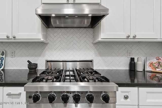 kitchen with extractor fan, dark countertops, backsplash, white cabinetry, and range with gas stovetop