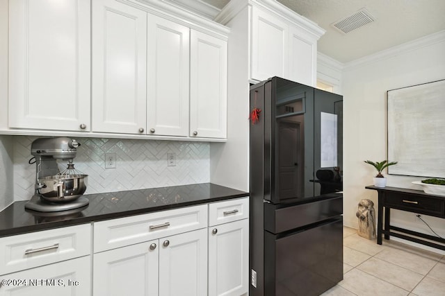 kitchen with decorative backsplash, freestanding refrigerator, ornamental molding, dark countertops, and visible vents