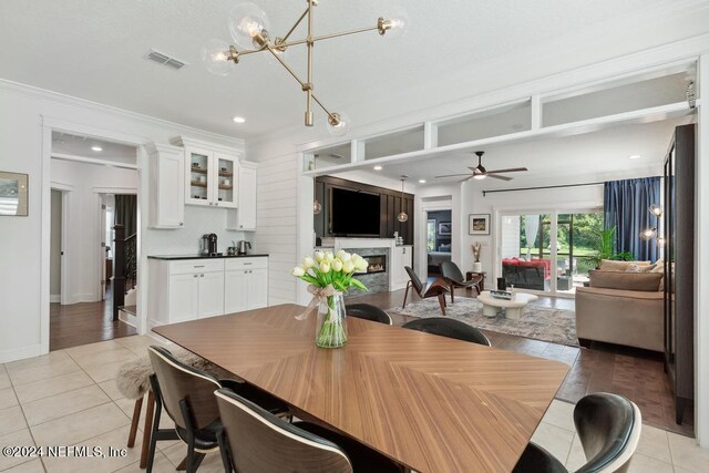dining area featuring light tile patterned floors, visible vents, recessed lighting, a fireplace, and ceiling fan with notable chandelier