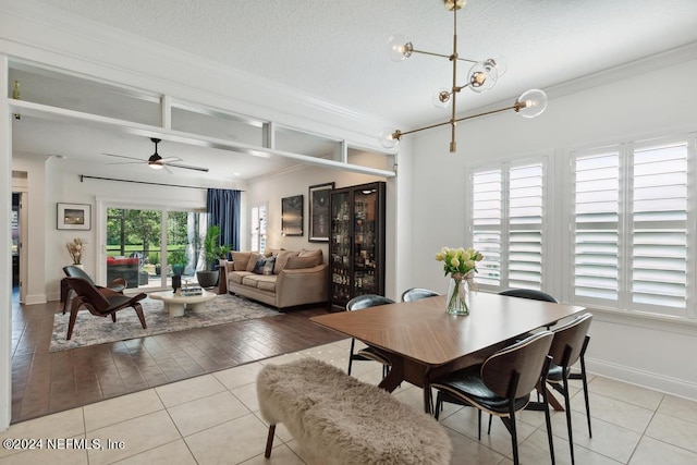 tiled dining room with crown molding, a textured ceiling, and ceiling fan with notable chandelier