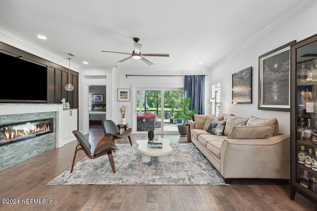 living room featuring a fireplace, a ceiling fan, ornamental molding, a textured ceiling, and wood finished floors