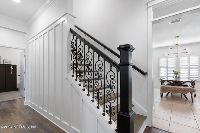 stairway with crown molding, a notable chandelier, and tile patterned flooring