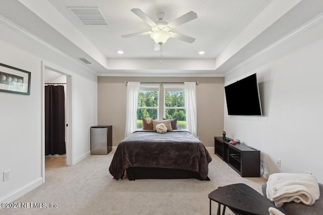 bedroom with a raised ceiling, light colored carpet, and ceiling fan