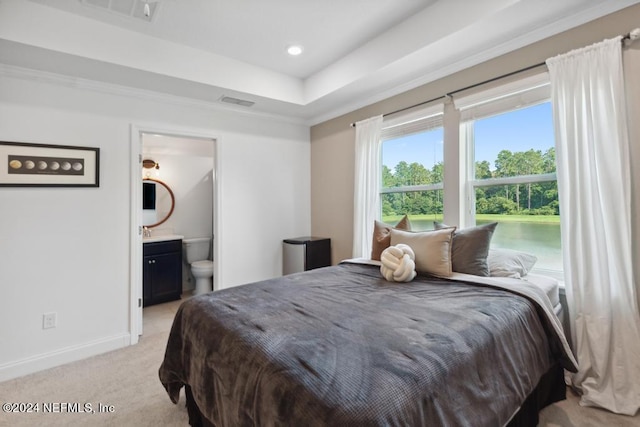 bedroom with a raised ceiling, visible vents, light carpet, baseboards, and ensuite bathroom