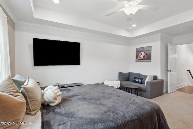 carpeted bedroom featuring ceiling fan, ornamental molding, and a tray ceiling