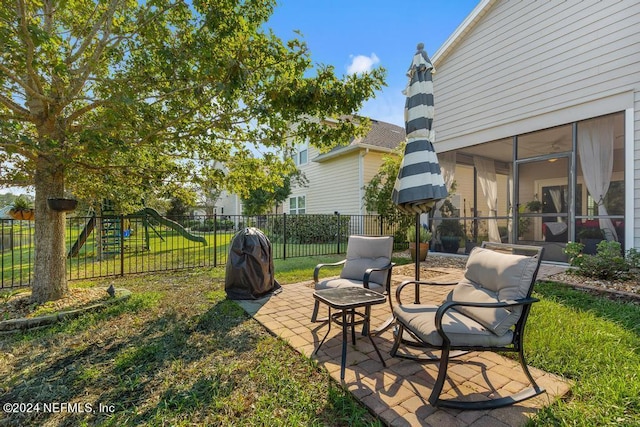 view of yard featuring fence, a playground, a patio, and a sunroom