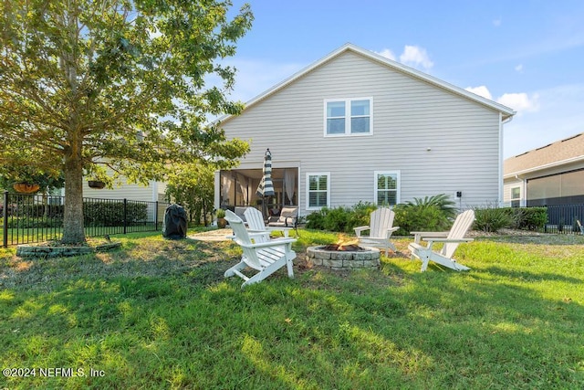 rear view of house featuring a yard, a sunroom, and a fire pit