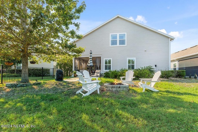 back of house with a lawn, fence, and an outdoor fire pit
