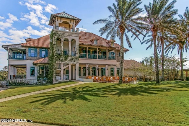 rear view of house featuring stucco siding, a balcony, and a tile roof