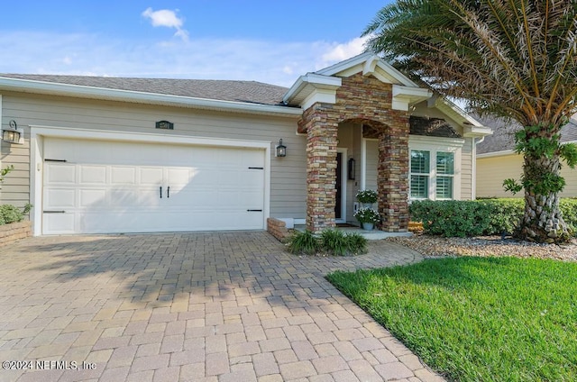 view of front of property featuring a garage, a shingled roof, and decorative driveway