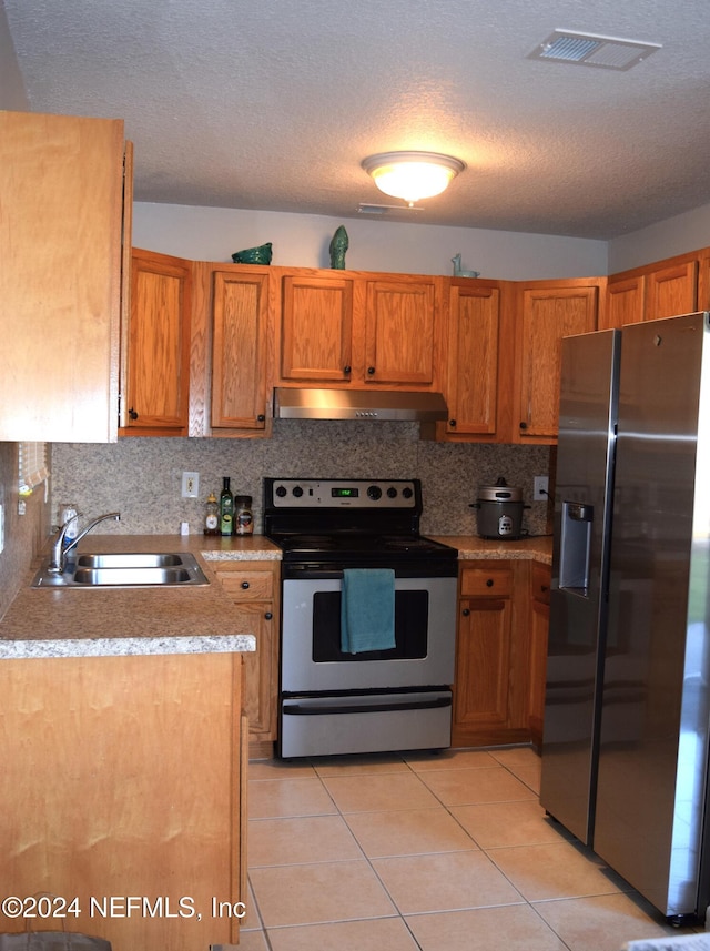 kitchen with decorative backsplash, stainless steel appliances, sink, light tile patterned floors, and a textured ceiling