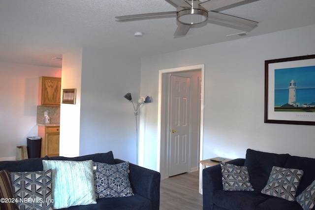 living room featuring ceiling fan, a textured ceiling, and light hardwood / wood-style flooring