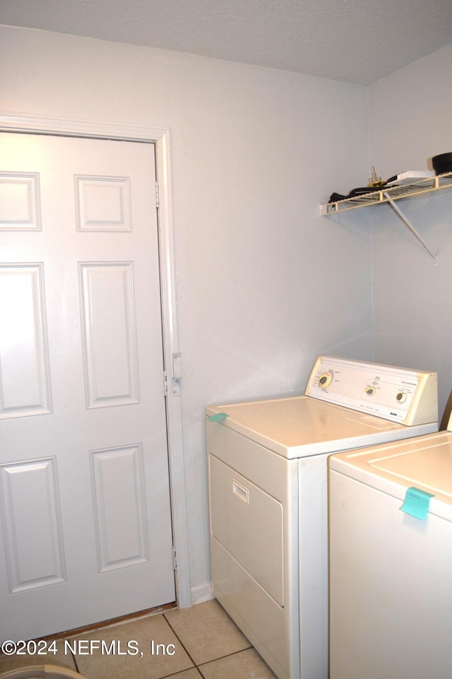 clothes washing area with washing machine and dryer and light tile patterned floors