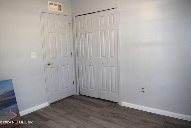 unfurnished bedroom featuring a closet and dark hardwood / wood-style flooring