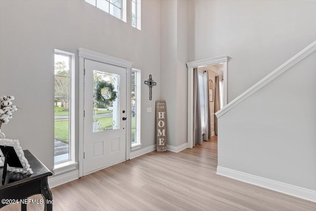 foyer featuring a towering ceiling and light hardwood / wood-style flooring