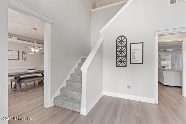 stairway featuring a notable chandelier, hardwood / wood-style flooring, and a towering ceiling