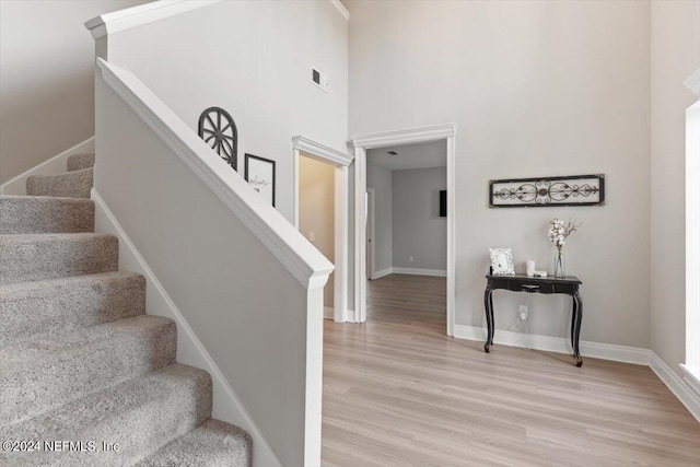 stairway with hardwood / wood-style floors and a high ceiling