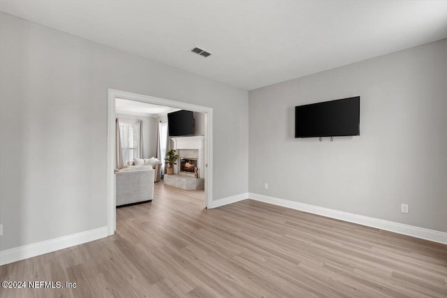 unfurnished living room featuring light wood-type flooring and a fireplace