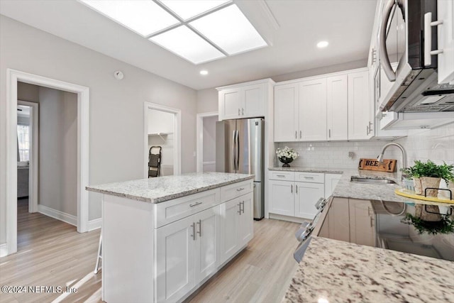 kitchen featuring sink, stainless steel appliances, a center island, and white cabinets