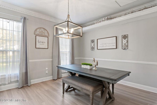 dining area with hardwood / wood-style flooring, ornamental molding, and a chandelier