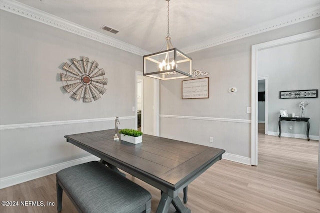 dining area with a notable chandelier, crown molding, and light wood-type flooring