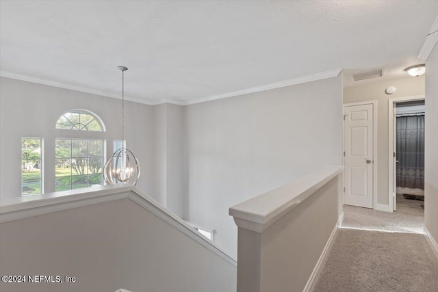 corridor featuring light colored carpet, ornamental molding, and a chandelier