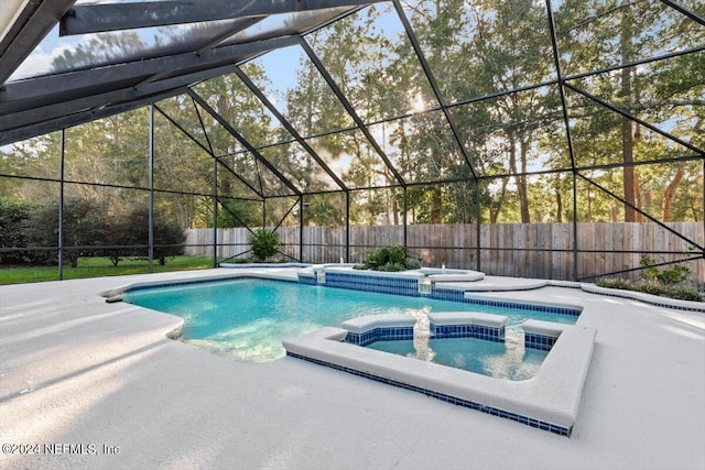 view of pool with a patio area, glass enclosure, and an in ground hot tub