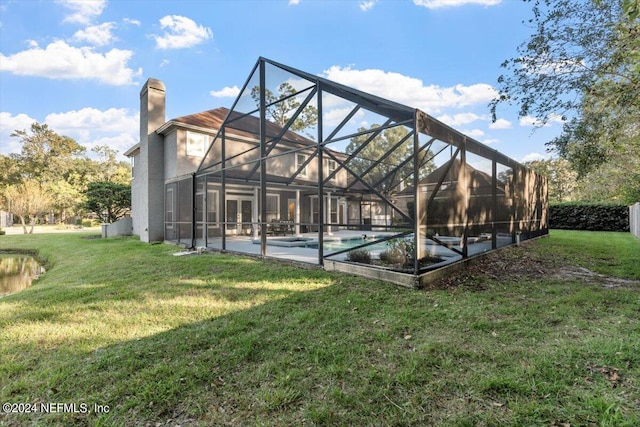 back of house with a yard and a lanai