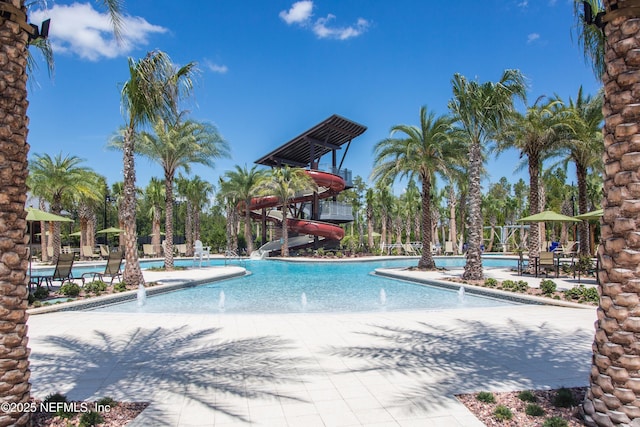 view of swimming pool with pool water feature, a water slide, and a patio