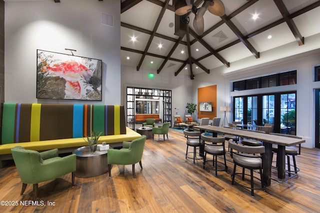 game room featuring hardwood / wood-style flooring, beam ceiling, and a high ceiling