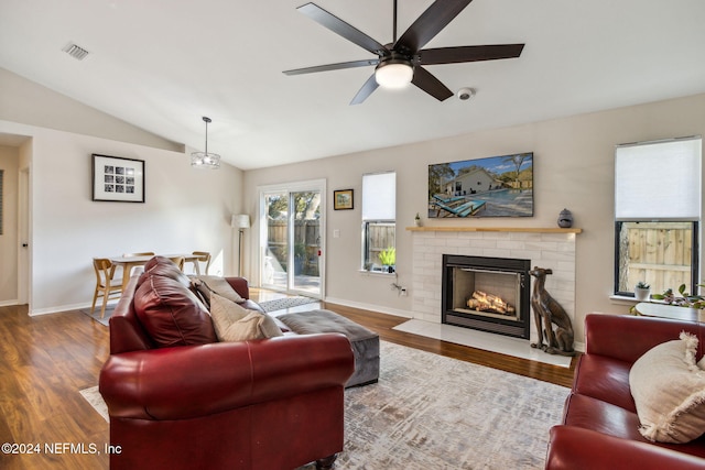 living room featuring ceiling fan, hardwood / wood-style flooring, lofted ceiling, and a brick fireplace