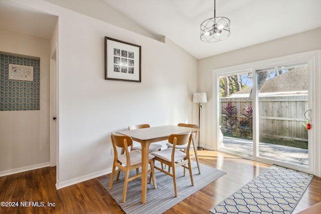 dining room with hardwood / wood-style flooring, vaulted ceiling, and an inviting chandelier