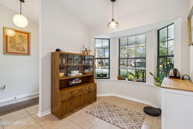 dining space with vaulted ceiling and light tile patterned flooring