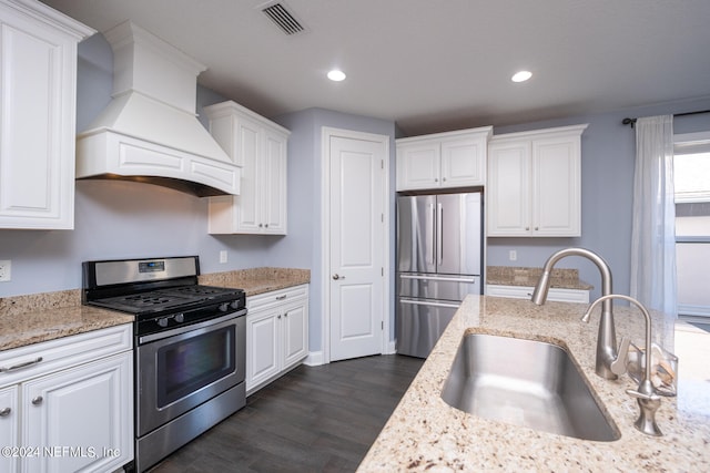 kitchen with appliances with stainless steel finishes, custom range hood, dark wood-type flooring, sink, and white cabinetry