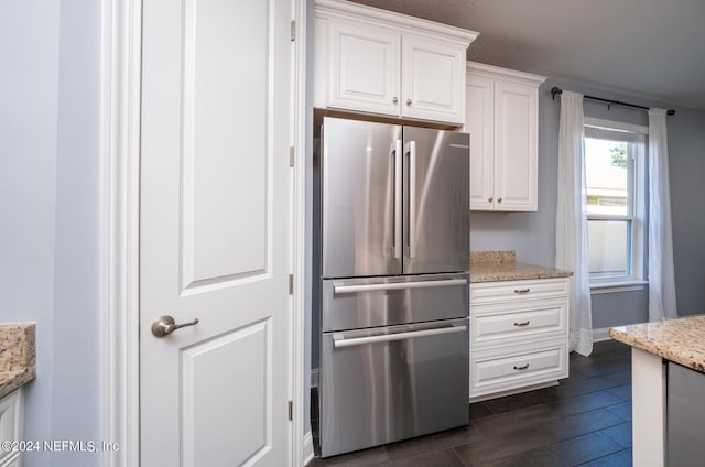 kitchen with white cabinets, stainless steel refrigerator, and light stone counters