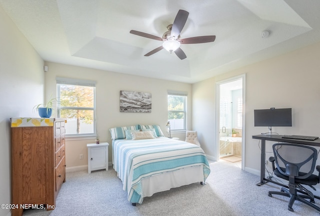 carpeted bedroom featuring connected bathroom, a raised ceiling, and ceiling fan