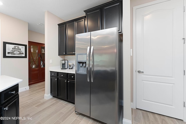 kitchen featuring stainless steel fridge, light hardwood / wood-style flooring, and decorative backsplash